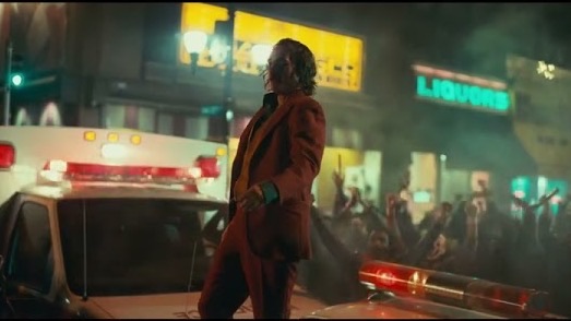 Joker standing on a police car in the city at night